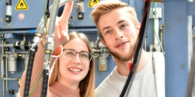 Zwei Studierende beobachten begeistert laufende Maschinen