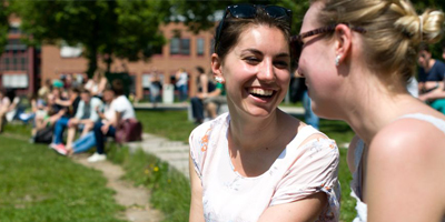 Bild von lachenden Studierenden an der Universität im Freien